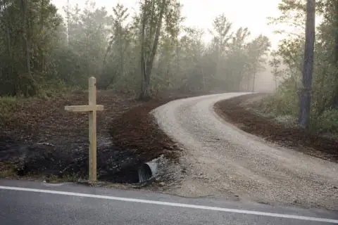 Fresh limestone lane winding into newly opened brush, drainage pipe bedded under the road entrance